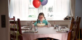 gehandicapt meisje zit alleen aan tafel
